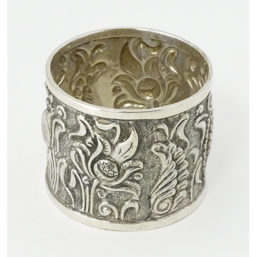 469 - A Continental white metal napkin ring  with floral and foliate detail, indistinctly marked to rim TO... 