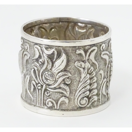 469 - A Continental white metal napkin ring  with floral and foliate detail, indistinctly marked to rim TO... 