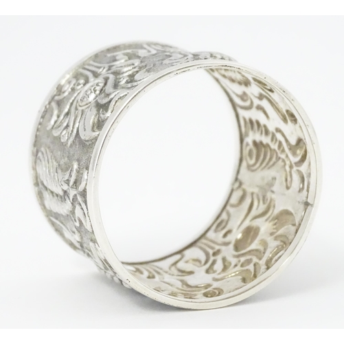 469 - A Continental white metal napkin ring  with floral and foliate detail, indistinctly marked to rim TO... 