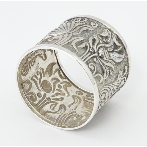 469 - A Continental white metal napkin ring  with floral and foliate detail, indistinctly marked to rim TO... 