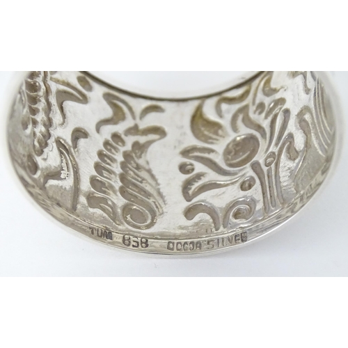 469 - A Continental white metal napkin ring  with floral and foliate detail, indistinctly marked to rim TO... 