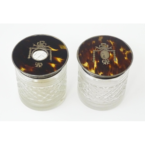 484 - A pair of cut glass dressing table jars the silver and tortoiseshell lids with pique decoration, one... 