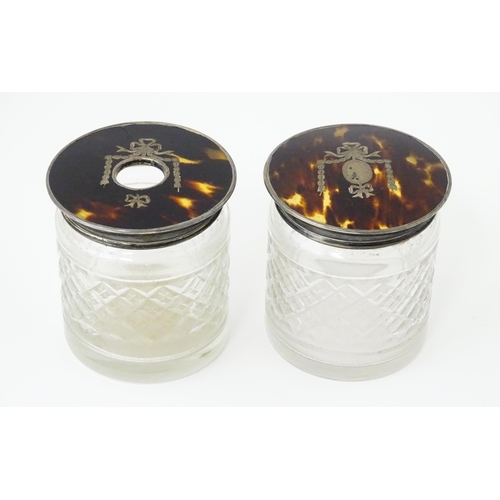 484 - A pair of cut glass dressing table jars the silver and tortoiseshell lids with pique decoration, one... 