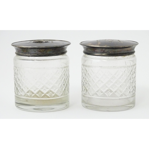 484 - A pair of cut glass dressing table jars the silver and tortoiseshell lids with pique decoration, one... 