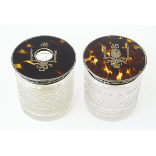 484 - A pair of cut glass dressing table jars the silver and tortoiseshell lids with pique decoration, one... 