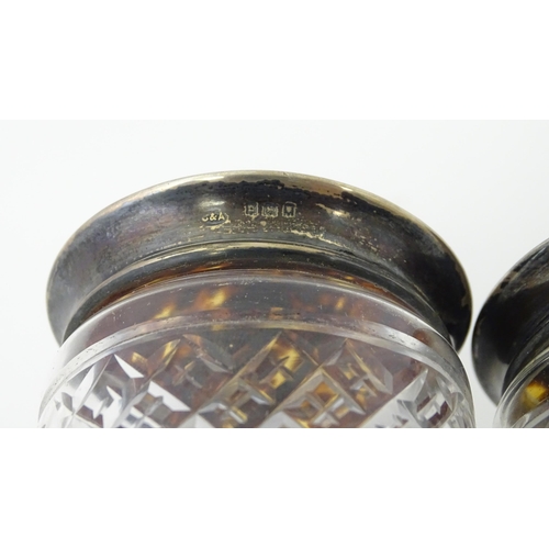 484 - A pair of cut glass dressing table jars the silver and tortoiseshell lids with pique decoration, one... 