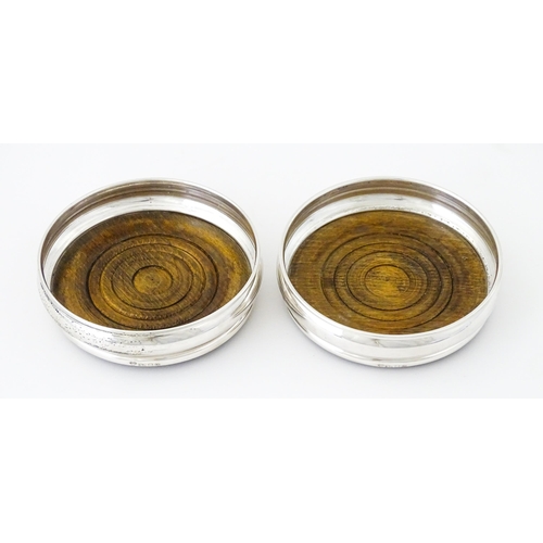 497 - A pair of silver bottle coasters with turned wooden bases, hallmarked London 1978, maker Da-Mar Silv... 