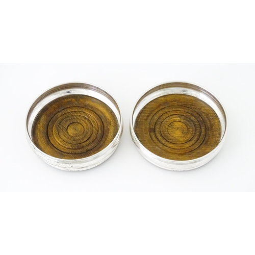 497 - A pair of silver bottle coasters with turned wooden bases, hallmarked London 1978, maker Da-Mar Silv... 