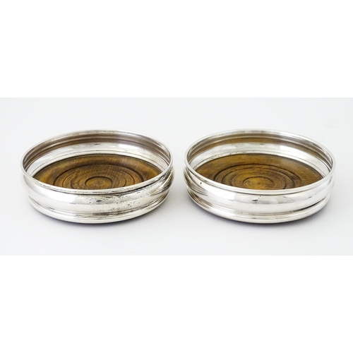 497 - A pair of silver bottle coasters with turned wooden bases, hallmarked London 1978, maker Da-Mar Silv... 