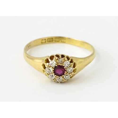 600 - An 18ct gold ring set with central ruby bordered by diamonds. Ring size approx. V 1/2