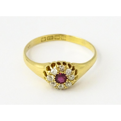 600 - An 18ct gold ring set with central ruby bordered by diamonds. Ring size approx. V 1/2