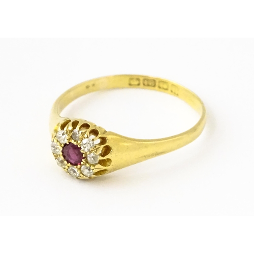 600 - An 18ct gold ring set with central ruby bordered by diamonds. Ring size approx. V 1/2