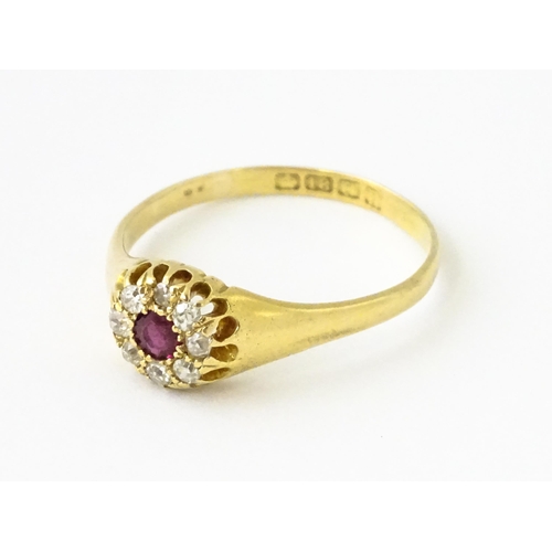 600 - An 18ct gold ring set with central ruby bordered by diamonds. Ring size approx. V 1/2