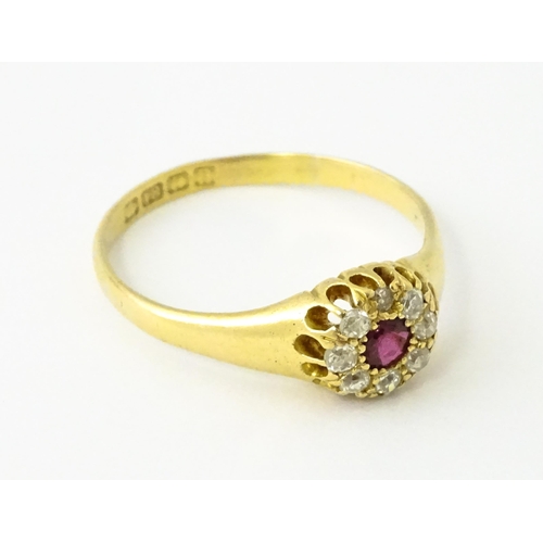 600 - An 18ct gold ring set with central ruby bordered by diamonds. Ring size approx. V 1/2