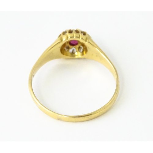 600 - An 18ct gold ring set with central ruby bordered by diamonds. Ring size approx. V 1/2