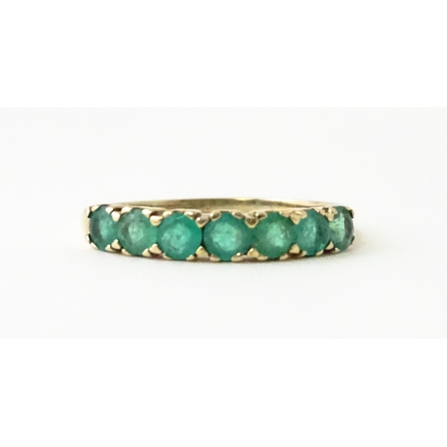 601 - A 10k gold ring set with emeralds in a linear setting. Ring size approx. R.