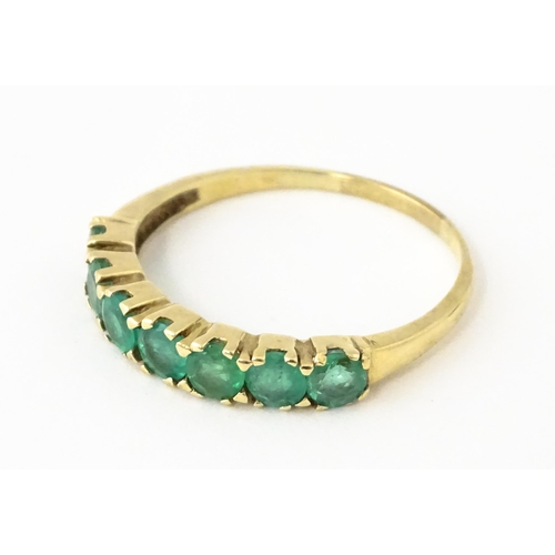 601 - A 10k gold ring set with emeralds in a linear setting. Ring size approx. R.