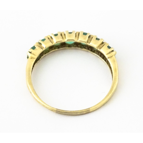 601 - A 10k gold ring set with emeralds in a linear setting. Ring size approx. R.