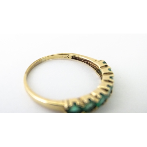 601 - A 10k gold ring set with emeralds in a linear setting. Ring size approx. R.