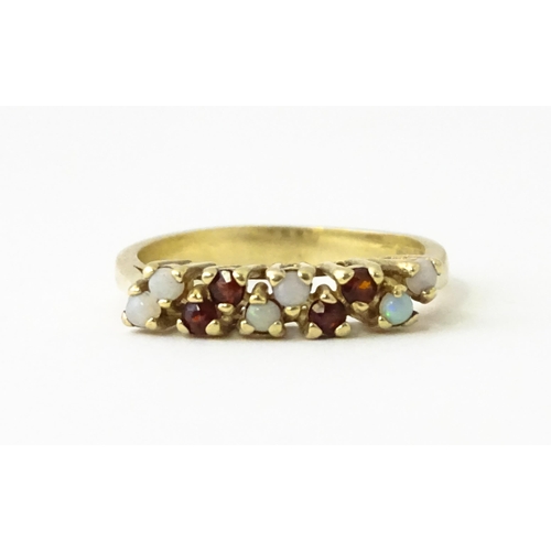 609 - A 9ct gold ring set with opals and garnets. Ring size approx. M 1/2