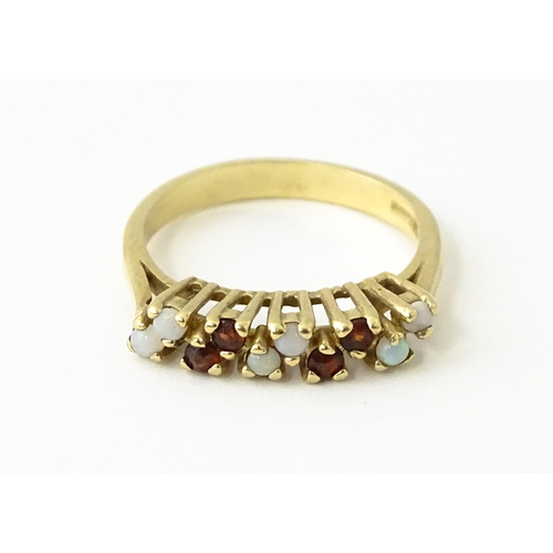 609 - A 9ct gold ring set with opals and garnets. Ring size approx. M 1/2