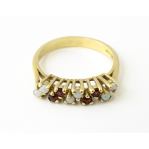 609 - A 9ct gold ring set with opals and garnets. Ring size approx. M 1/2