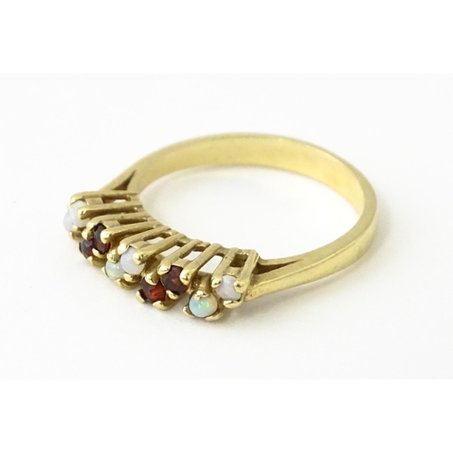 609 - A 9ct gold ring set with opals and garnets. Ring size approx. M 1/2