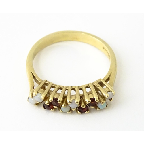 609 - A 9ct gold ring set with opals and garnets. Ring size approx. M 1/2