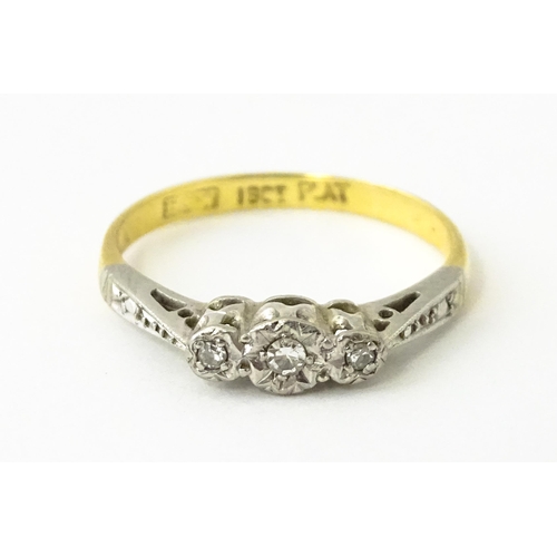 611 - An 18ct gold ring with three platinum set diamonds, maker Eaton & Wrighton. Ring size approx. K