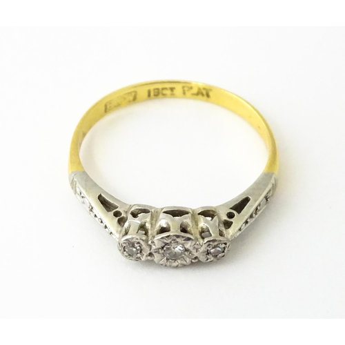 611 - An 18ct gold ring with three platinum set diamonds, maker Eaton & Wrighton. Ring size approx. K