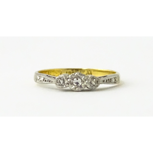 611 - An 18ct gold ring with three platinum set diamonds, maker Eaton & Wrighton. Ring size approx. K