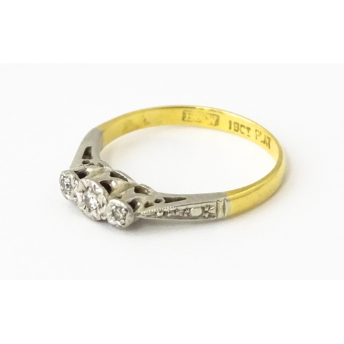 611 - An 18ct gold ring with three platinum set diamonds, maker Eaton & Wrighton. Ring size approx. K