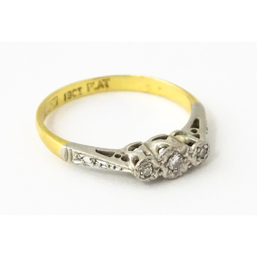 611 - An 18ct gold ring with three platinum set diamonds, maker Eaton & Wrighton. Ring size approx. K