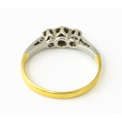 611 - An 18ct gold ring with three platinum set diamonds, maker Eaton & Wrighton. Ring size approx. K