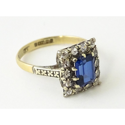 612 - A 9ct gold ring set with central sapphire bordered by white stones.  Ring size approx. M