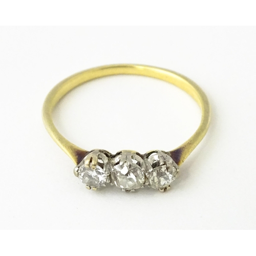 613 - A gold ring set with a trio of diamonds.  Ring size approx. O