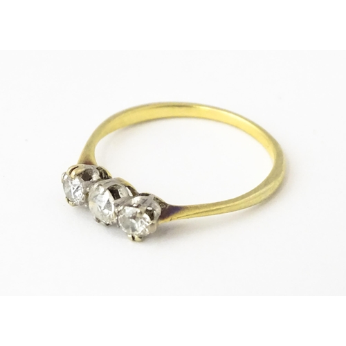 613 - A gold ring set with a trio of diamonds.  Ring size approx. O