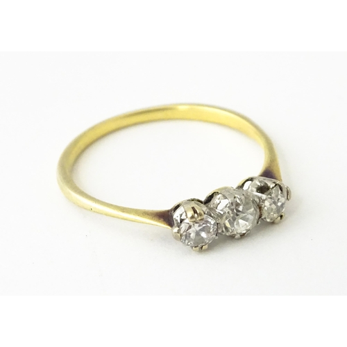 613 - A gold ring set with a trio of diamonds.  Ring size approx. O