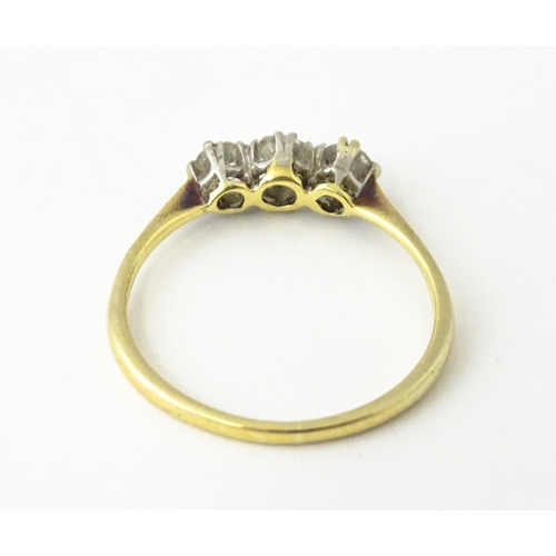 613 - A gold ring set with a trio of diamonds.  Ring size approx. O