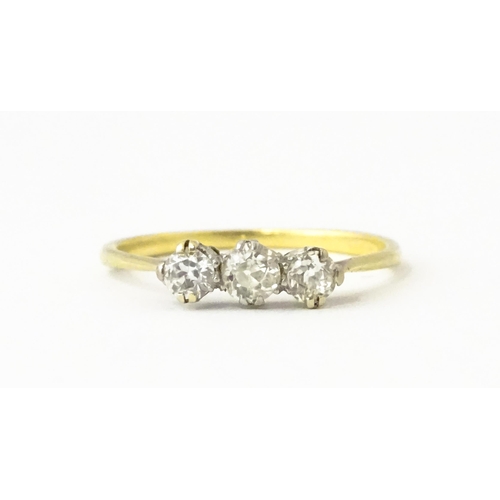 613 - A gold ring set with a trio of diamonds.  Ring size approx. O