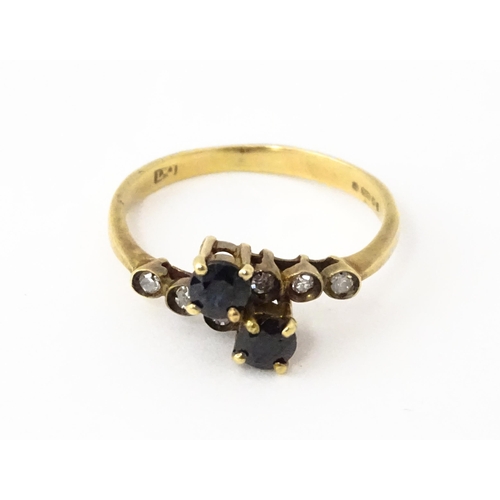 616 - A 9ct gold ring set with two blue stones flanked by three diamonds to each shoulder. Ring size appro... 