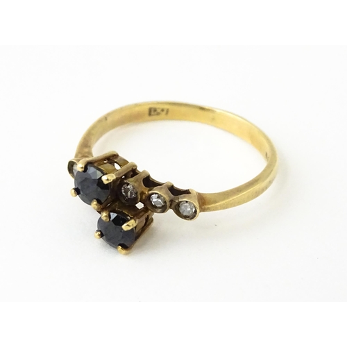 616 - A 9ct gold ring set with two blue stones flanked by three diamonds to each shoulder. Ring size appro... 