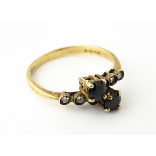 616 - A 9ct gold ring set with two blue stones flanked by three diamonds to each shoulder. Ring size appro... 