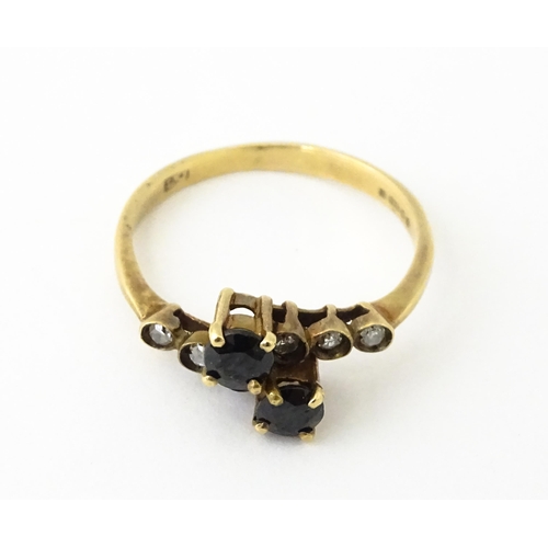 616 - A 9ct gold ring set with two blue stones flanked by three diamonds to each shoulder. Ring size appro... 