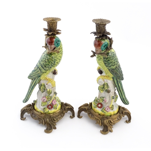 1255 - A pair of late 20thC ceramic candlesticks, the stem formed as a parrot perched on a branch with flow... 