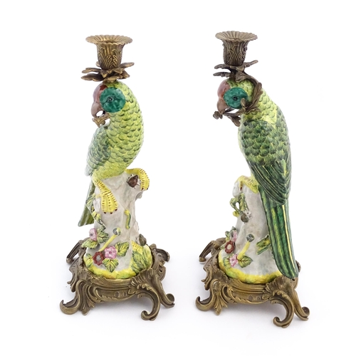 1255 - A pair of late 20thC ceramic candlesticks, the stem formed as a parrot perched on a branch with flow... 