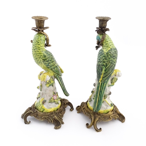 1255 - A pair of late 20thC ceramic candlesticks, the stem formed as a parrot perched on a branch with flow... 