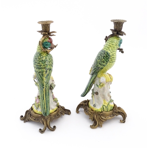 1255 - A pair of late 20thC ceramic candlesticks, the stem formed as a parrot perched on a branch with flow... 