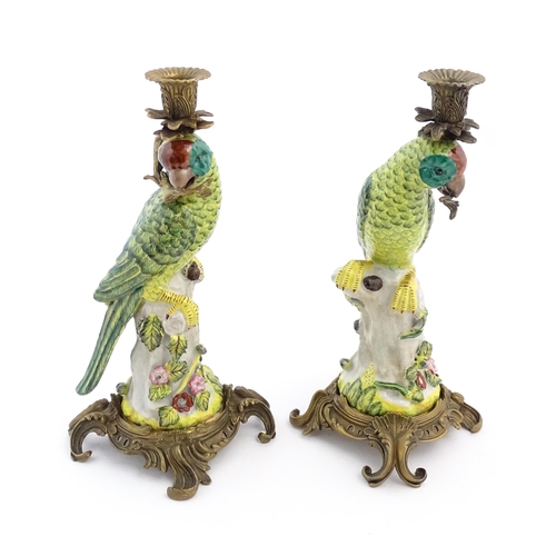 1255 - A pair of late 20thC ceramic candlesticks, the stem formed as a parrot perched on a branch with flow... 