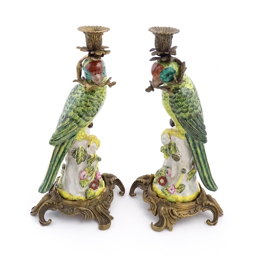 1255 - A pair of late 20thC ceramic candlesticks, the stem formed as a parrot perched on a branch with flow... 